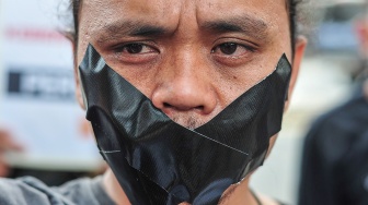 Salah seorang jurnalis yang tergabung dalam Koalisi Anti Pembungkaman Demokrasi melakukan aksi diam sambil membentangkan poster di Mapolda Jambi, Jambi, Rabu (17/9/2025). [ANTARA FOTO/Wahdi Septiawan/bar]
