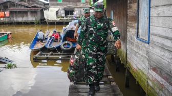 Prajurit TNI AD anggota Kodim 0906/Kutai Kartanegara, Peltu Suhendro (depan) didampingi Babinsa Loa Ipuh Serda Eri Yudin Robiyanto (belakang) berjalan dari perahu klinik terapung saat akan melakukan pemeriksaan kesehatan warga di kawasan Loa Ipuh, Tenggarong, Kutai Kartanegara, Kalimantan Timur, Jumat (19/9/2025). [ANTARA FOTO/M Risyal Hidayat/tom]