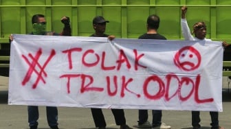 Pengunjuk rasa membentangkan spanduk saat mengikuti aksi menuntut penertiban truk berdimensi dan bermuatan lebih atau overdimension-overload (ODOL) di Jalan Lingkar Selatan, Kota Cilegon, Banten, Kamis (16/10/2025). [ANTARA FOTO/Angga Budhiyanto/nym]
