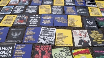 Deretan poster dari Koalisi Bersihkan Indonesia (KBI) saat menggelar aksi simbolik di Taman Pandang Istana, Jakarta, Senin (20/10/2025). [Suara.com/Alfian Winanto]
