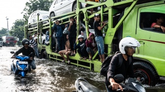 Sejumlah warga menumpang truk untuk dapat menembus banjir yang menggenangi jalur utama pantura Semarang-Surabaya di Jalan Kaligawe Raya, Semarang, Jawa Tengah, Jumat (24/10/2025). [ANTARA FOTO/Aprillio Akbar/YU]