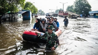 Personel Babinsa Koramil 06/Genuk menggunakan perahu karet untuk mengangkut pasien dan tenaga kesehatan saat banjir melanda jalur utama Pantura Semarang - Surabaya di Jalan Kaligawe Raya, Semarang, Jawa Tengah, Jumat (24/10/2025). [ANTARA FOTO/Aprillio Akbar/YU]