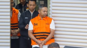 Gubernur Riau Abdul Wahid (tengah) mengenakan rompi oranye khas tahanan KPK usai ditetapkan sebagai tersangka korupsi di Gedung Merah Putih KPK, Jakarta, Rabu (5/11/2025). [Suara.com/Alfian Winanto]