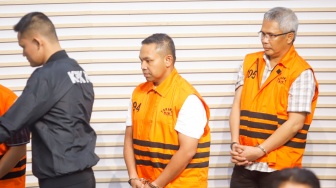 Gubernur Riau Abdul Wahid (tengah) mengenakan rompi oranye khas tahanan KPK usai ditetapkan sebagai tersangka korupsi di Gedung Merah Putih KPK, Jakarta, Rabu (5/11/2025). [Suara.com/Alfian Winanto]