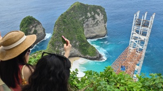 Wisatawan melihat pemandangan di samping bangunan lift kaca di tebing kawasan wisata Pantai Kelingking, Nusa Penida, Klungkung, Bali, Rabu (5/11/2025). [ANTARA FOTO/Fikri Yusuf/nym]