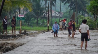 Warga melintasi lahar hujan Gunung Semeru yang meluap dari Sungai Regoyo di Desa Gondoruso, Kecamatan Pasirian, Lumajang, Jawa Timur, Rabu (5/11/2025). [ANTARA FOTO/Irfan Sumanjaya/nym]
