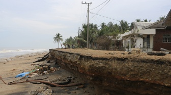 Pengendara sepeda motor melintas di atas badan jalan yang amblas tergerus abrasi pantai di Desa Lhok Puuk, Seunudon, Aceh Utara, Aceh, Sabtu (8/11/2025). [ANTARA FOTO/Syifa Yulinnas/rwa]
