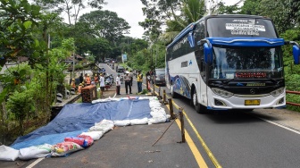 Polisi mengatur arus lalu lintas saat kendaraan melewati jembatan yang longsor di Jembatan Cikaleho, Kecamatan Cipaku, Kabupaten Ciamis, Jawa Barat, Sabtu (8/11/2025). [ANTARA FOTO/Adeng Bustomi/rwa]
