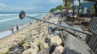 Wisatawan berjalan di dekat jalur pejalan kaki yang rusak di Pantai Kuta, Badung, Bali, Rabu (12/11/2025). [ANTARA FOTO/Fikri Yusuf/rwa]