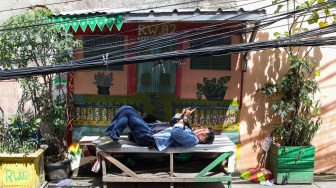 Warga beraktivitas di dekat jaringan kabel utilitas yang menjuntai di kawasan Setiabudi, Jakarta, Rabu (12/11/2025). [Suara.com/Alfian Winanto]