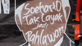 Poster tolak Soeharto menjadi pahlawan saat mengikuti Aksi Kamisan ke-886 di depan Istana Merdeka, Jakarta, Kamis (13/11/2025). [Suara.com/Alfian Winanto]
