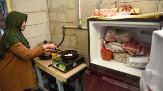 Warga memasak menggunakan kompor biogas saat peresmian pemanfaatan biogas melalui instalasi tangki septik komunal oleh Gubernur DKI Jakarta Pramono Anung di permukiman Gang Delta, Pekayon, Pasar Rebo, Jakarta Timur, Kamis (13/11/2025). [ANTARA FOTO/Indrianto Eko Suwarso/bar]