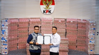 Plt Deputi Penindakan dan Eksekusi KPK Asep Guntur Rahayu (kanan) memberikan berita acara penyerahan hasil rampasan aset hasil korupsi kepada Direktur Utama PT Taspen, Rony Hanityo Aprianto (kiri) di Gedung Merah Putih KPK, Jakarta, Kamis (20/11/2025). [Suara.com/Alfian Winanto]