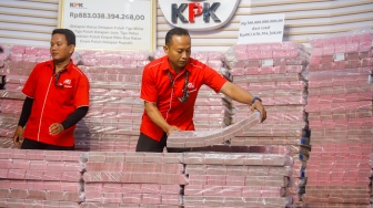 Petugas menyusun tumpukan aset hasil rampasan senilai kurang lebih Rp 883 miliar (ditampilkan Rp 300 miliar) diserahkan KPK kepada PT. Taspen (Persero) di Gedung Merah Putih KPK, Jakarta, Kamis (20/11/2025). [Suara.com/Alfian Winanto]