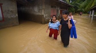 Sejumlah warga melintasi banjir yang merendam Nagari Kampuang Galapuang, Ulakan Tapakis, Padang Pariaman, Sumatera Barat, Selasa (25/11/2025). [ANTARA FOTO/Iggoy el Fitra/bar]