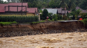 Warga berada di tepi jalan penghubung antar desa yang longsor akibat luapan sungai di Nagari Salibutan, Lubuk Alung, Padang Pariaman, Sumatera Barat, Selasa (25/11/2025). [ANTARA FOTO/Iggoy el Fitra/bar]
