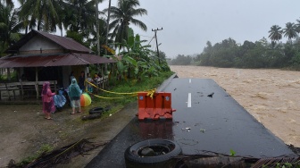 Warga berada di tepi jalan penghubung antar desa yang longsor akibat luapan sungai di Nagari Salibutan, Lubuk Alung, Padang Pariaman, Sumatera Barat, Selasa (25/11/2025). [ANTARA FOTO/Iggoy el Fitra/bar]

