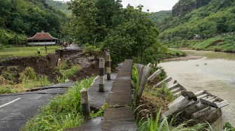 Warga berjalan melewati area persawahan di dekat jalan penghubung desa yang amblas di Sriharjo, Bantul, DI Yogyakarta, Rabu (26/11/2025). [ANTARA FOTO/Hendra Nurdiyansyah/foc]