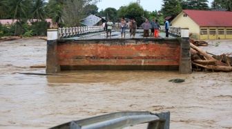 Warga menyaksikan jembatan lintas jalur nasional putus akibat diterjang banjir bandang di Desa Manyang Cut, Kecamatan Mereudu, Kabupaten Pidie, Aceh, Kamis (27/11/2025). [ANTARA FOTO/Ampelsa/foc]