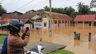 Seorang warga mengabadikan suasana Sekolah Dasar Negeri Teupin Peuraho yang diliburkan akibat banjir di Desa Teupin Peuraho, Arongan Lambalek, Aceh Barat, Aceh, Kamis (27/11/2025). [ANTARA FOTO/Syifa Yulinnas/foc]