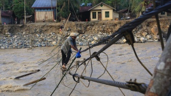 Sejumlah warga melintasi jembatan alternatif yang menghubungkan Desa Blang Meurandeh dan Desa Blang Puuk Beutong Ateuh Banggalang, Nagan Raya, Aceh, Minggu (30/11/2025). [ANTARA FOTO/Syifa Yulinnas/nz]