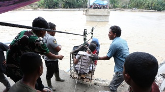 Warga menggunakan kabel baja yang untuk menyeberangi Sungai Juli pascaputusnya Jembatan Juli di jalan lintas Bireuen - Takengon, Aceh, Selasa (2/12/2025). [ANTARA FOTO/Irwansyah Putra/bar]