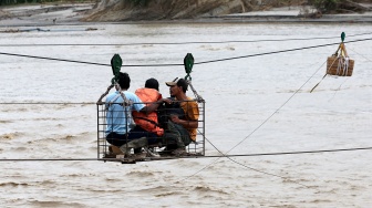 Warga menggunakan kabel baja yang untuk menyeberangi Sungai Juli pascaputusnya Jembatan Juli di jalan lintas Bireuen - Takengon, Aceh, Selasa (2/12/2025). [ANTARA FOTO/Irwansyah Putra/bar]