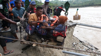 Warga menggunakan kabel baja yang untuk menyeberangi Sungai Juli pascaputusnya Jembatan Juli di jalan lintas Bireuen - Takengon, Aceh, Selasa (2/12/2025). [ANTARA FOTO/Irwansyah Putra/bar]