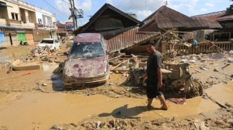 Warga melintas di dekat mobil warga yang terbawa arus banjir di kawasan Desa Bukit Tempurung, Kota Kuala Simpang, Kabupaten Aceh Tamiang, Aceh, Rabu (3/12/2025). [ANTARA FOTO/Syifa Yulinnas/nz]