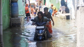 Warga mendorong kendaraannya yang mogok saat melintasi banjir rob di Muara Angke, Jakarta, Jumat (5/12/2025). [Suara.com/Alfian Winanto]
