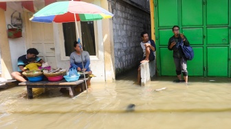 Warga beraktivitas saat banjir rob di Muara Angke, Jakarta, Jumat (5/12/2025). [Suara.com/Alfian Winanto]