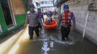 Petugas membantu warga melintasi banjir rob dengan perahu di Muara Angke, Jakarta, Jumat (5/12/2025). [Suara.com/Alfian Winanto]