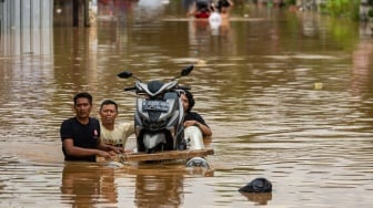 Warga mendorong perahu yang membawa sepeda motor saat melintasi banjir di Baleendah, Kabupaten Bandung, Jawa Barat, Sabtu (6/12/2025). [ANTARA FOTO/Novrian Arbi/foc]