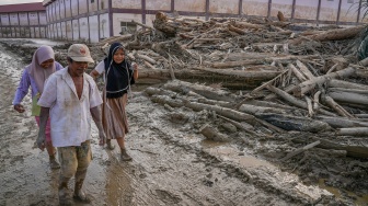 Sejumlah warga melewati kayu-kayu yang memenuhi area Pondok Pesantren Darul Mukhlishin pascabanjir bandang di Desa Tanjung Karang, Karang Baru, Kabupaten Aceh Tamiang, Aceh, Jumat (5/12/2025). [ANTARA FOTO/Erlangga Bregas Prakoso/app/foc]
