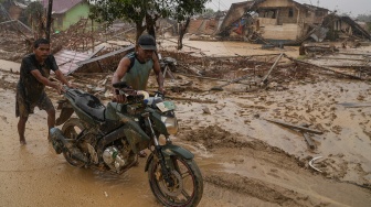 Warga mendorong sepeda motor melintas di desa yang luluh lantak pascabanjir di Desa Bundar, Karang Baru, Kabupaten Aceh Tamiang, Aceh, Selasa (9/12/2025). [ANTARA FOTO/Erlangga Bregas Prakoso/mrh/foc]