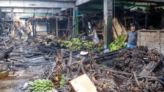 Pedagang melihat puing-puing sisa kebakaran di Pasar Induk Kramat Jati, Jakarta, Senin (15/12/2025). [Suara.com/Alfian Winanto]