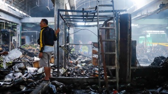 Pedagang melihat puing-puing sisa kebakaran di Pasar Induk Kramat Jati, Jakarta, Senin (15/12/2025). [Suara.com/Alfian Winanto]