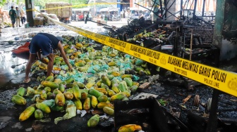 Pedagang memilih buah yang tersisa usai kebakaran di Pasar Induk Kramat Jati, Jakarta, Senin (15/12/2025). [Suara.com/Alfian Winanto]