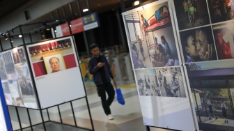 Calon penumpang melintasi sejumlah karya pada pameran Haluan Merah Putih di Stasiun Tanah Abang, Jakarta, Senin (15/12/2025). [Suara.com/Alfian Winanto]