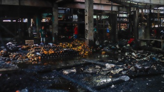Pedagang melihat puing-puing sisa kebakaran di Pasar Induk Kramat Jati, Jakarta, Senin (15/12/2025). [Suara.com/Alfian Winanto]