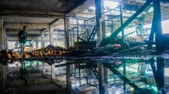 Pedagang melihat puing-puing sisa kebakaran di Pasar Induk Kramat Jati, Jakarta, Senin (15/12/2025). [Suara.com/Alfian Winanto]