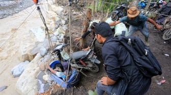 Warga membantu korban bencana yang terisolir saat menaiki derek pengangkut barang untuk melintasi Daerah Aliran Sungai (DAS) Peusangan dari Desa Bergang Kecamatan Ketol, Aceh Tengah dan Desa Simpang Rahmat, Gajah Putih, Bener Meriah, Aceh, Minggu (14/12/2025). [ANTARA FOTO/Syifa Yulinnas/nz]