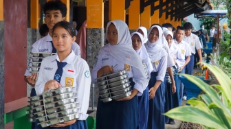 Para siswa membawa menu Makan Bergizi Gratis (MBG) untuk dibagikan ke kelas masing-masinh di SMPN 1 Tamansari, Bogor, Jawa Barat, Selasa (16/12/2025). [Suara.com/Alfian Winanto]