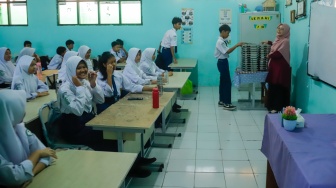 Siswa membagikan menu Makan Bergizi Gratis (MBG) untuk dibagikan ke kelas masing-masinh di SMPN 1 Tamansari, Bogor, Jawa Barat, Selasa (16/12/2025). [Suara.com/Alfian Winanto]