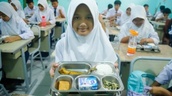 Siswa menunjukan menu Makan Bergizi Gratis (MBG) di SMPN 1 Tamansari, Bogor, Jawa Barat, Selasa (16/12/2025). [Suara.com/Alfian Winanto]