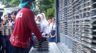 Petugas mendistribusikan menu Makan Bergizi Gratis (MBG) di SMPN 1Tamansari, Bogor, Selasa (16/12/2025). [Suara.com/Alfian Winanto]