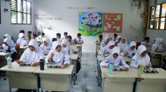 Para siswa menyantap menu Makan Bergizi Gratis (MBG) di SMPN 1 Tamansari, Bogor, Jawa Barat, Selasa (16/12/2025). [Suara.com/Alfian Winanto]