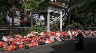 Pengendara sepeda motor melintas di dekat tumpukan sampah di Jalan Kihajar Dewantara, Ciputat, Tangerang Selatan, Banten, Sabtu (13/12/2025). [ANTARA FOTO/Sulthony Hasanuddin/tom]