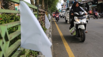 Sejumlah pengendara melintas didekat bendera putih yang terpasang di seputaran kota Meulaboh, Aceh Barat, Aceh, Rabu (17/12/2025). [ANTARA FOTO/Syifa Yulinnas/foc]