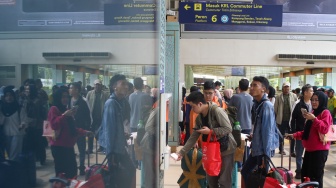 Penumpang menunggu kedatangan kereta api di Stasiun Pasar Senen, Jakarta Pusat, Senin (22/12/2025). [Suara.com/Alfian Winanto]